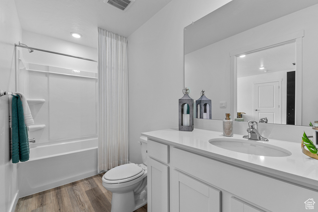 Bathroom featuring vanity, toilet, shower / bath combo with shower curtain, wood finished floors, and recessed lighting