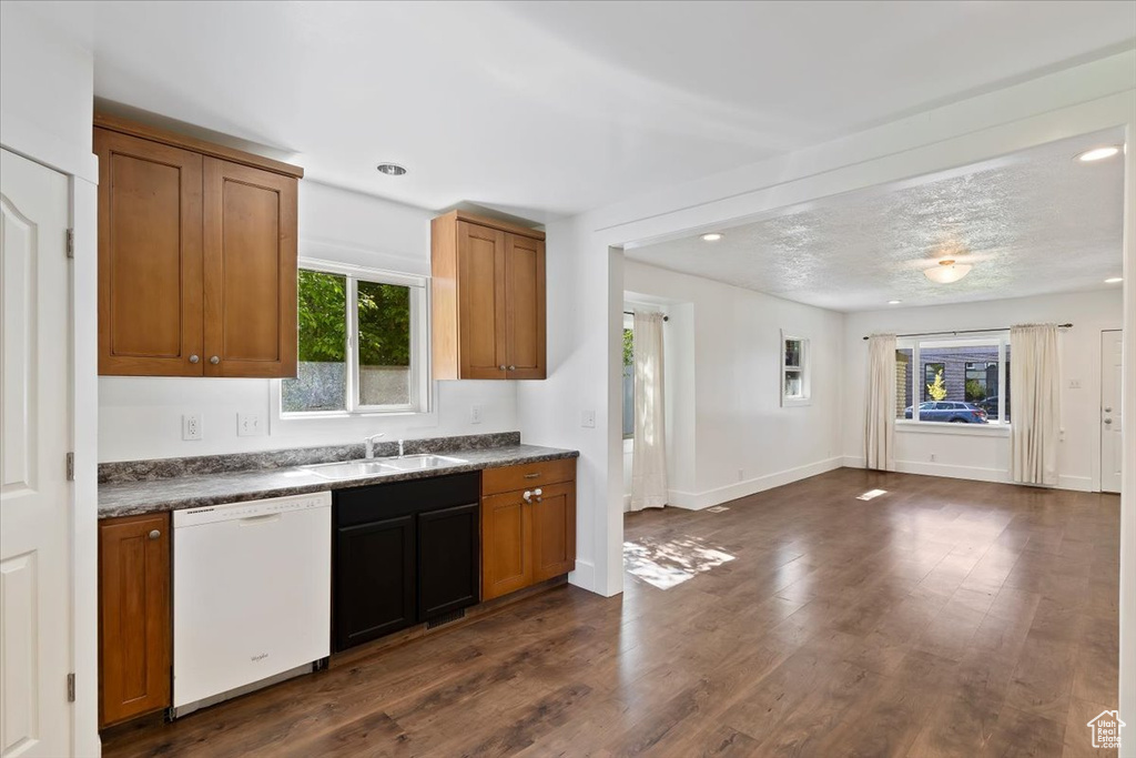 Kitchen with dishwasher, a sink, dark countertops, brown cabinetry, and dark wood finished floors
