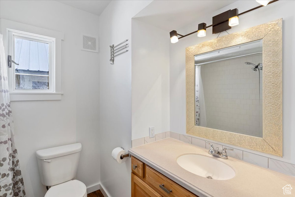 Bathroom featuring toilet, vanity, and a shower with shower curtain