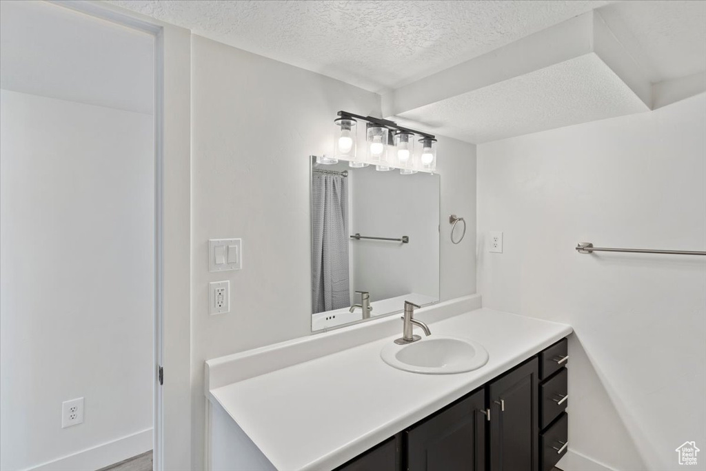 Bathroom featuring a textured ceiling, vanity, and baseboards