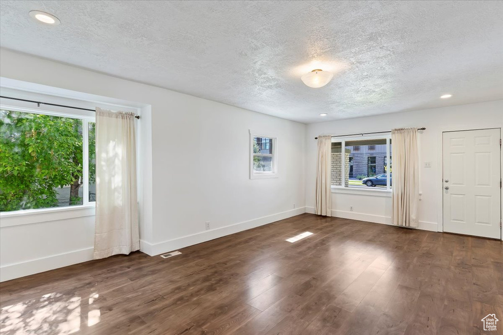 Unfurnished room with a textured ceiling, baseboards, wood finished floors, and recessed lighting