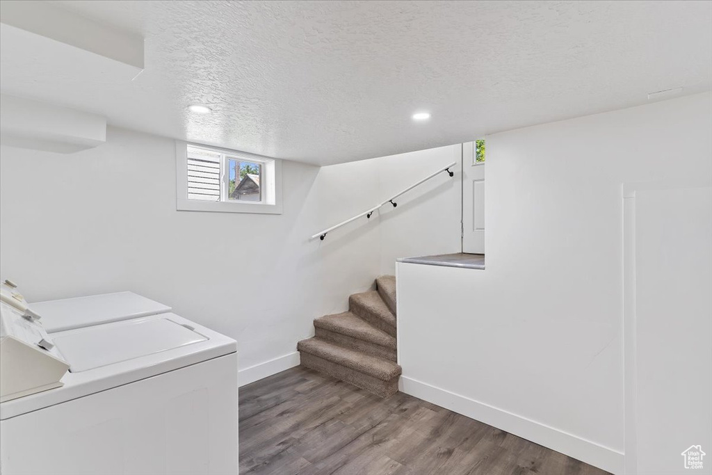 Washroom with washing machine and dryer, baseboards, wood finished floors, recessed lighting, and a textured ceiling