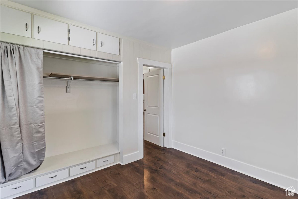 Unfurnished bedroom featuring dark wood-style floors, baseboards, and a closet