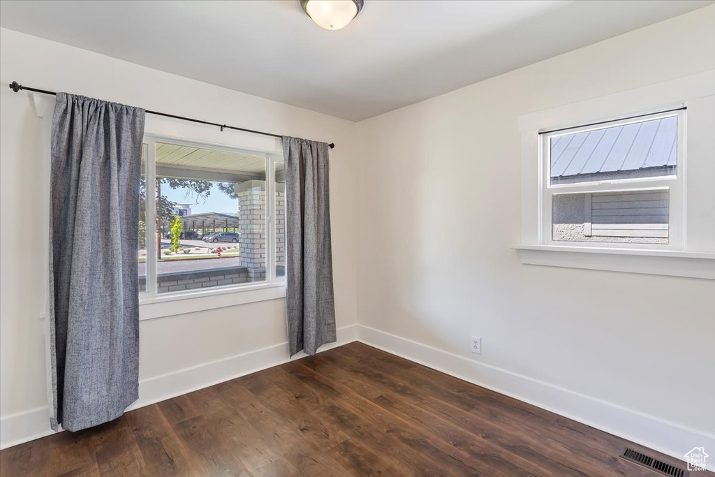 Empty room featuring baseboards and dark wood finished floors