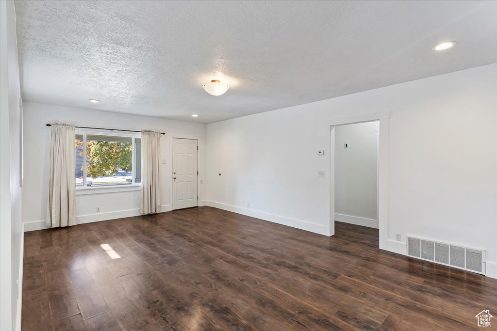 Unfurnished room featuring a textured ceiling, dark wood-style floors, baseboards, and recessed lighting
