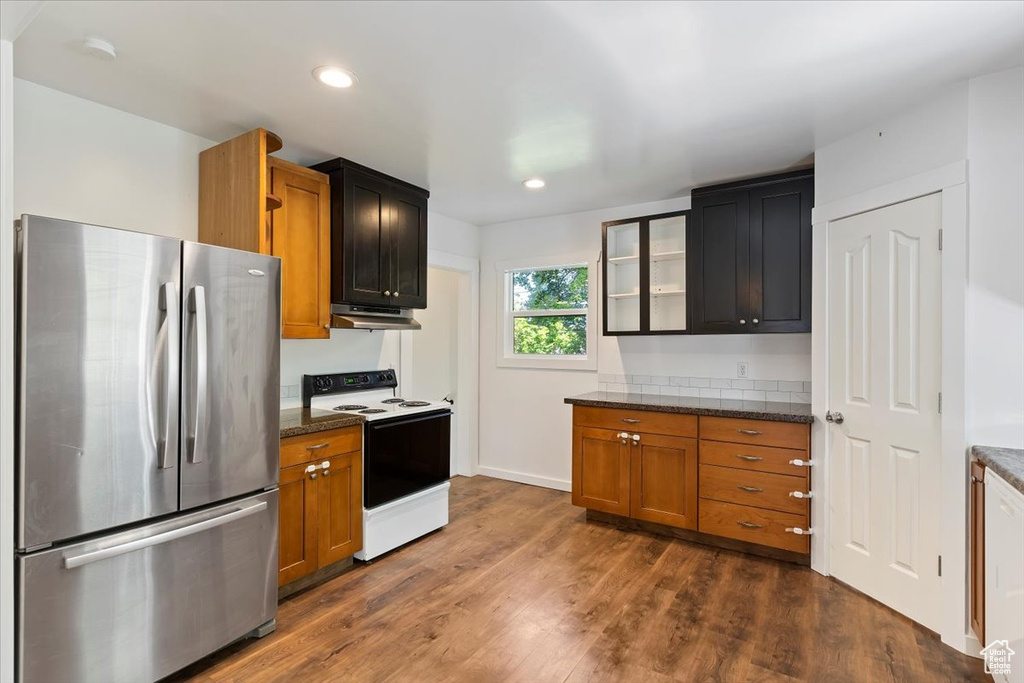 Kitchen with freestanding refrigerator, electric range oven, recessed lighting, dark wood-style floors, and under cabinet range hood