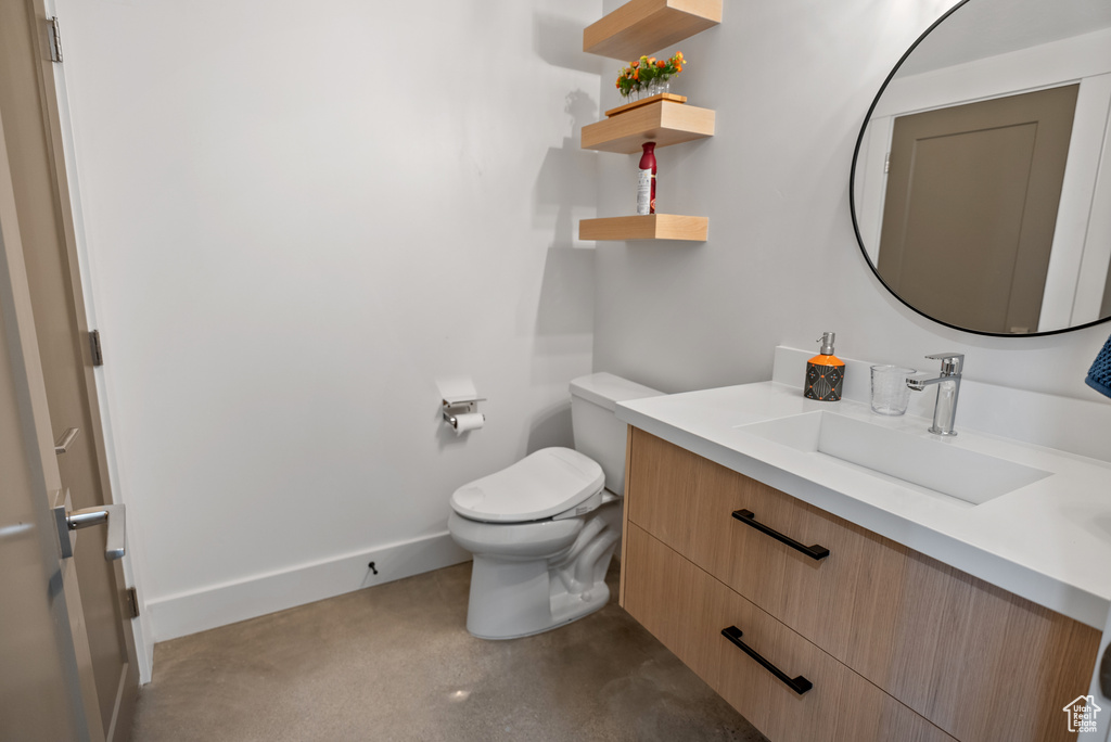 Half bathroom with vanity, toilet, and baseboards