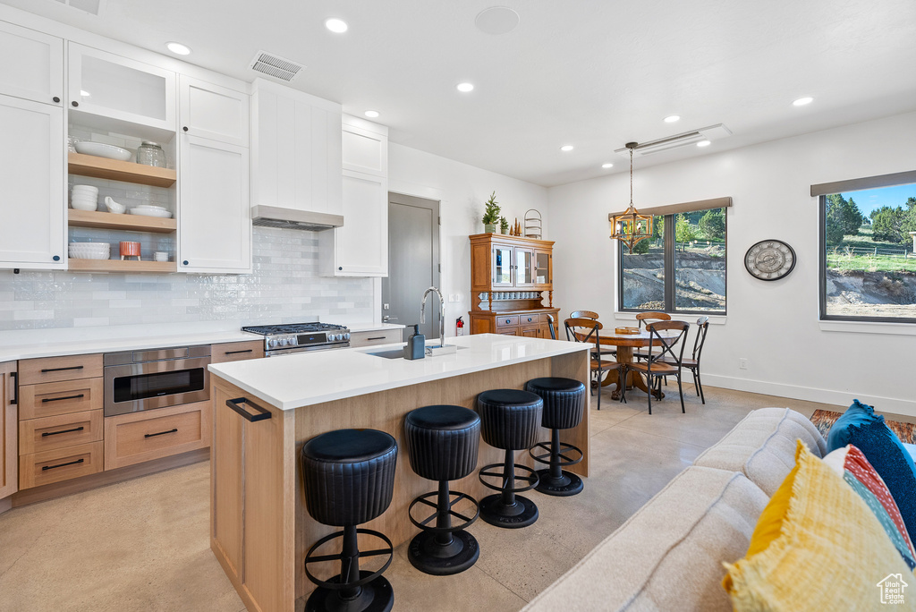 Kitchen with a sink, tasteful backsplash, recessed lighting, light countertops, and a breakfast bar