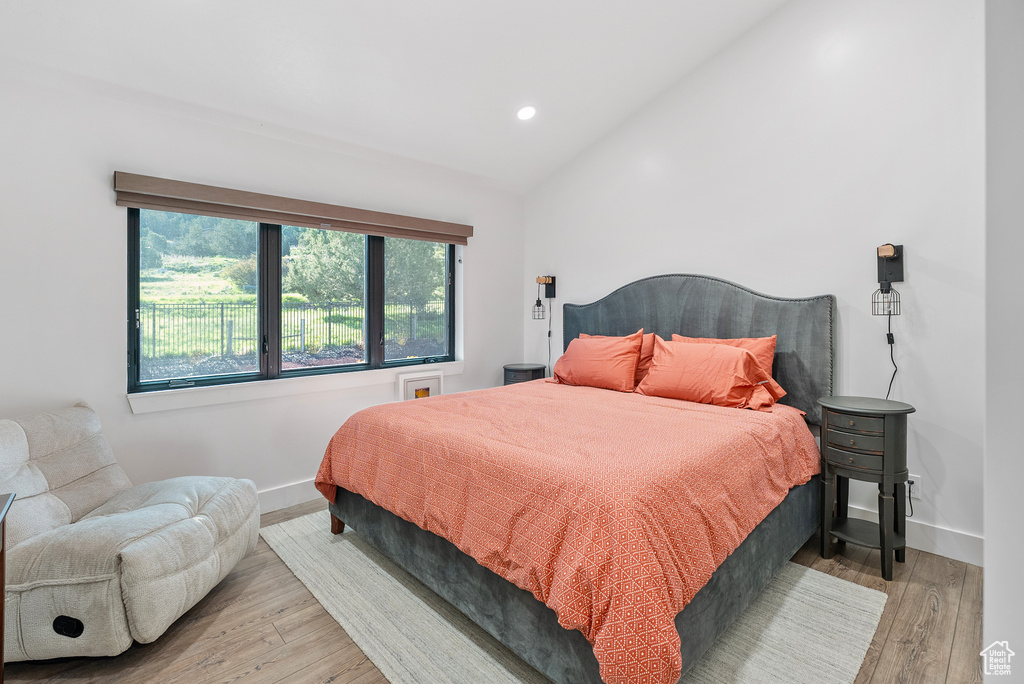 Bedroom with lofted ceiling, wood finished floors, baseboards, and recessed lighting
