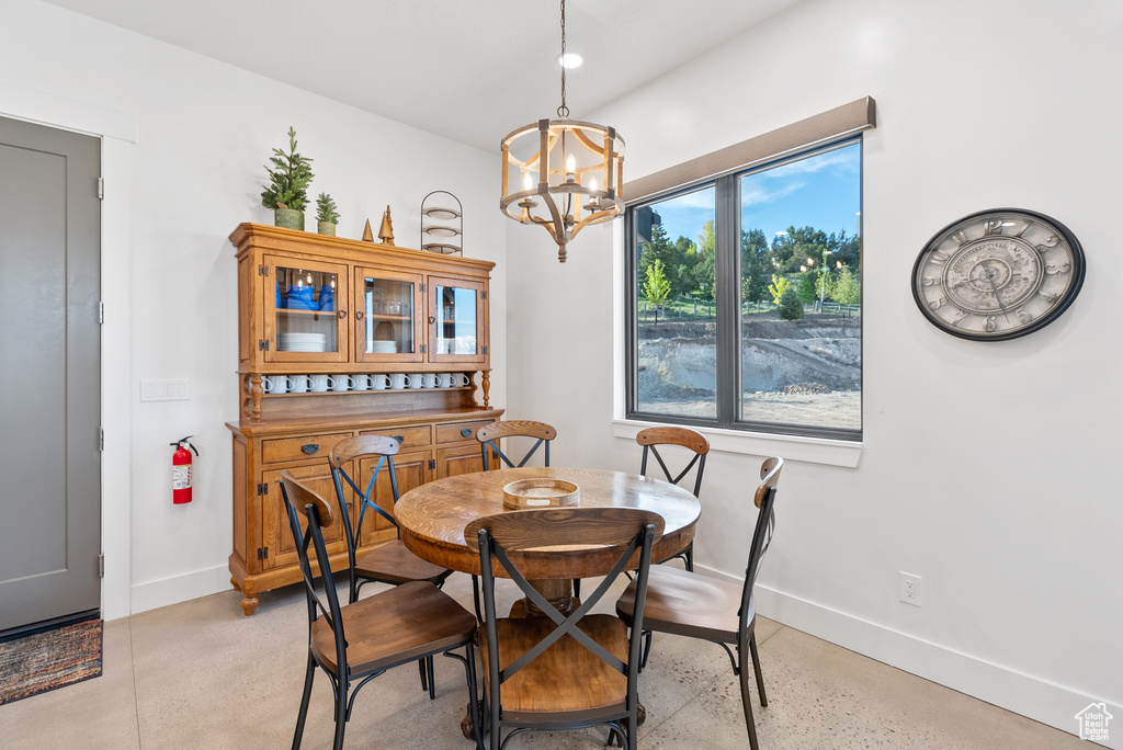 Dining space with baseboards, a chandelier, and concrete floors