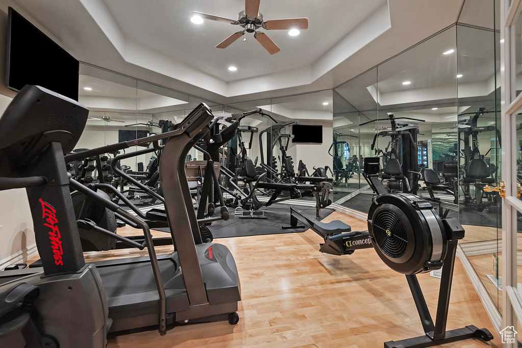 Gym featuring a ceiling fan, a raised ceiling, recessed lighting, and wood finished floors