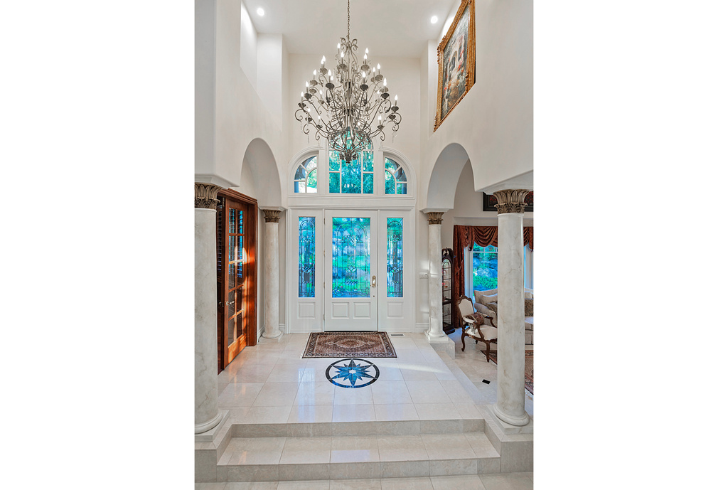 Entryway with decorative columns, arched walkways, a towering ceiling, a chandelier, and recessed lighting