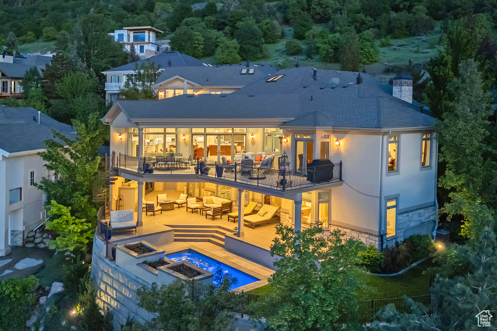Rear view of property featuring an outdoor living space with a fire pit, a balcony, a chimney, a patio, and a shingled roof