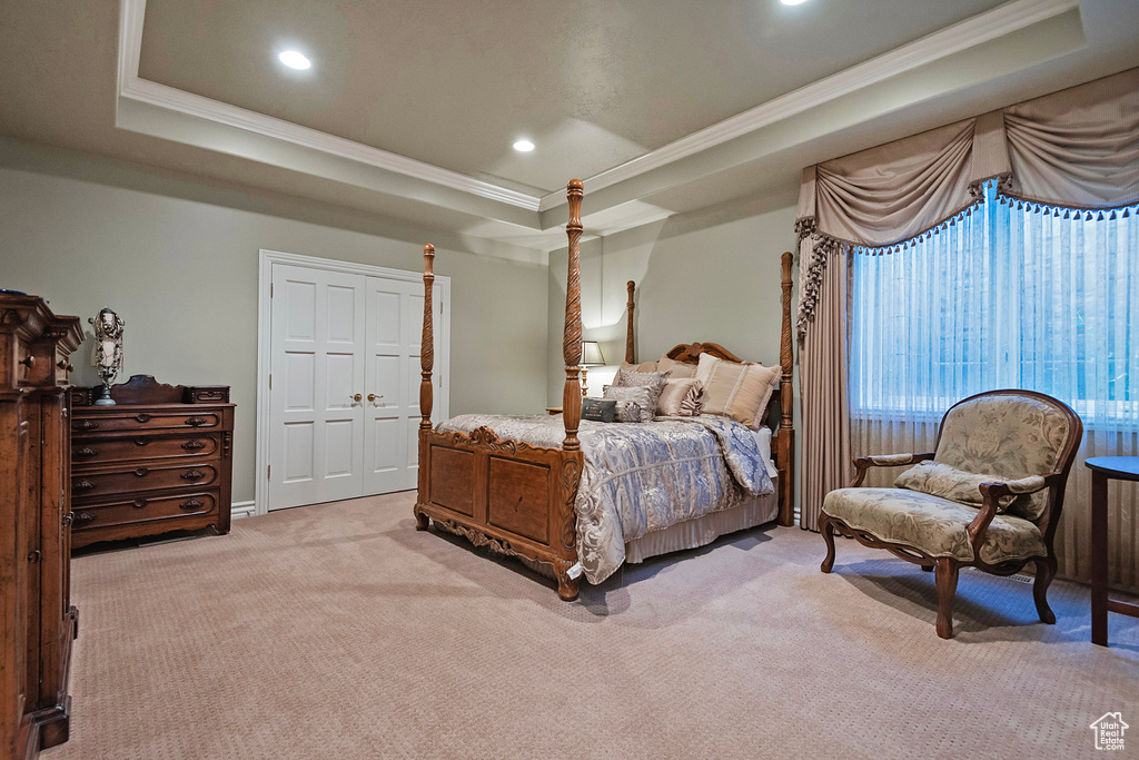 Bedroom with a tray ceiling, crown molding, light carpet, and recessed lighting