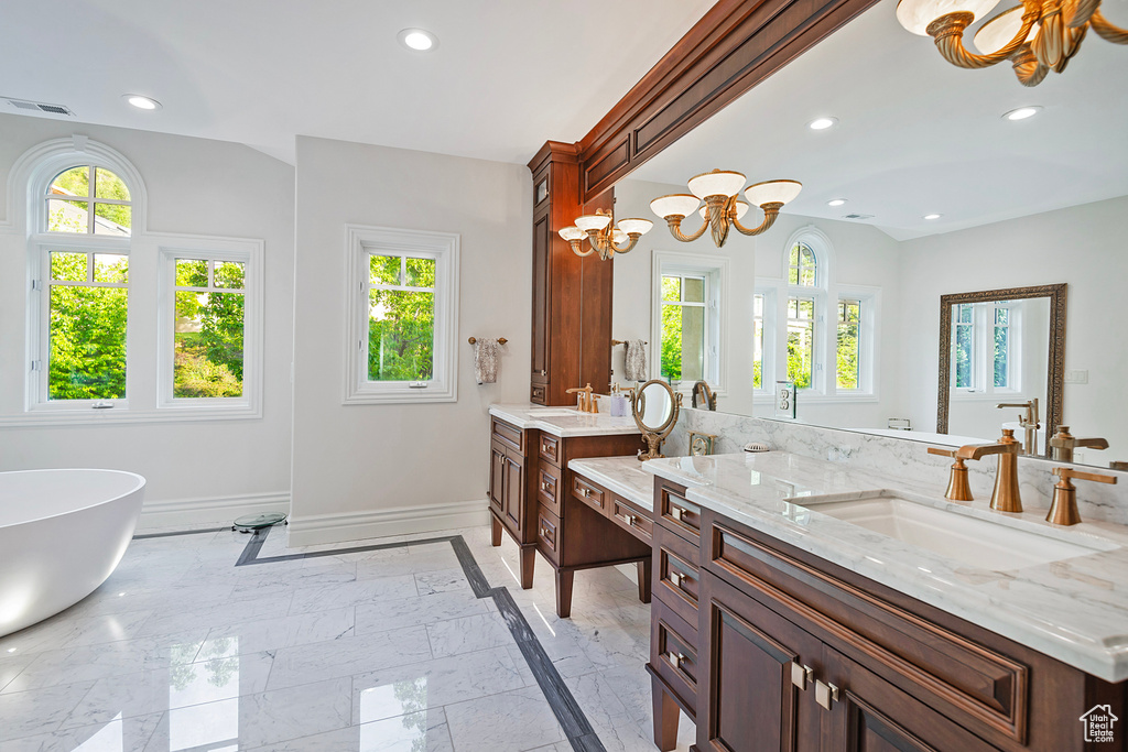 Bathroom featuring a chandelier, baseboards, vanity, a freestanding tub, and recessed lighting