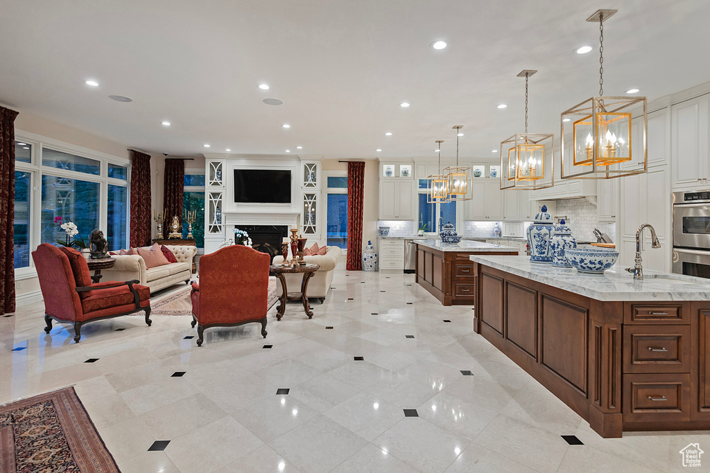 Kitchen with a spacious island, a sink, a chandelier, backsplash, and recessed lighting