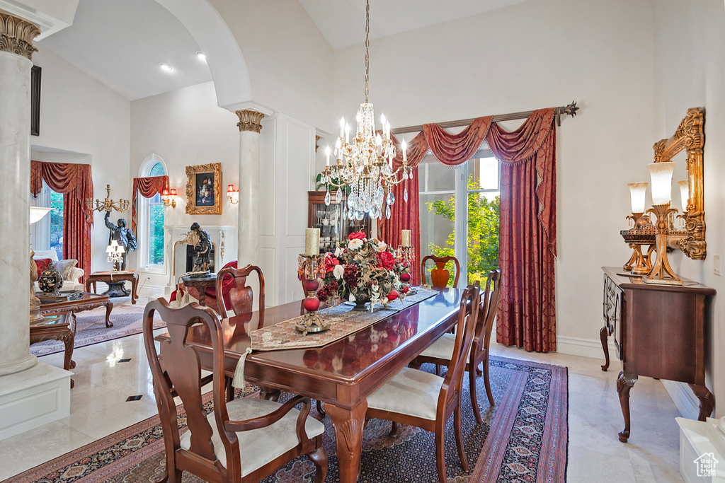 Dining room with arched walkways, a towering ceiling, a chandelier, and decorative columns