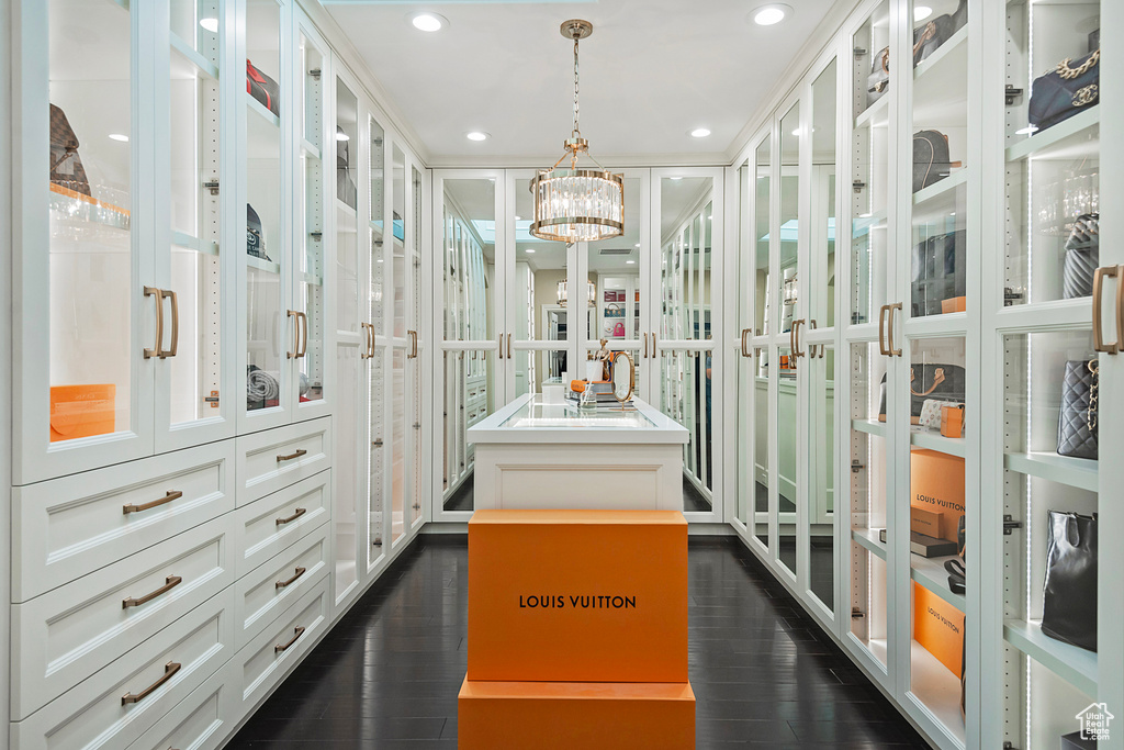 Spacious closet with dark wood-style floors and a chandelier