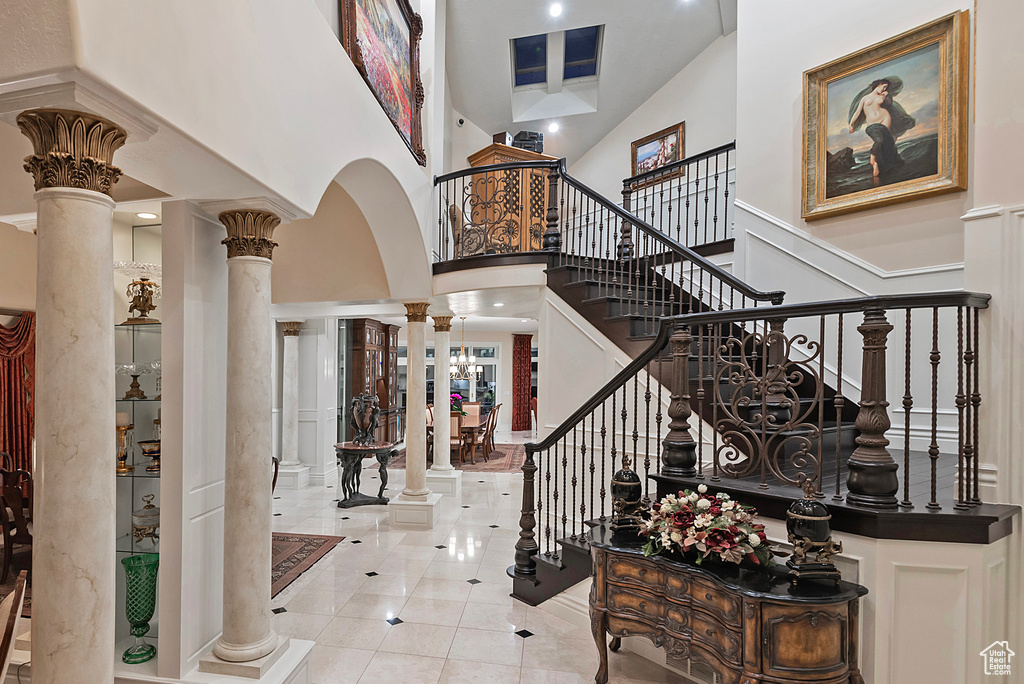 Tiled entrance foyer with decorative columns, a high ceiling, stairs, and arched walkways