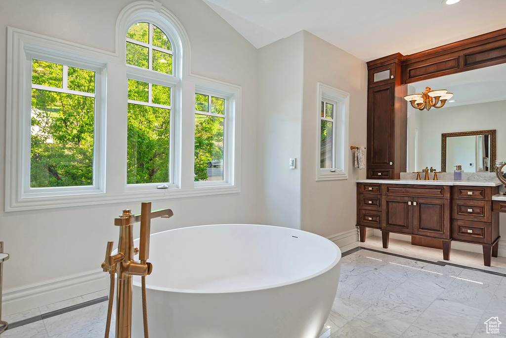 Bathroom featuring marble tiled flooring, vanity, baseboards, a freestanding bath, and recessed lighting