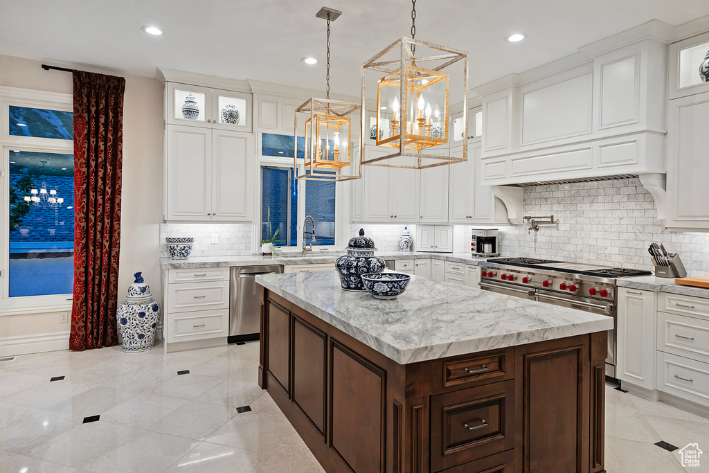 Kitchen with appliances with stainless steel finishes, a chandelier, a sink, a center island, and glass insert cabinets