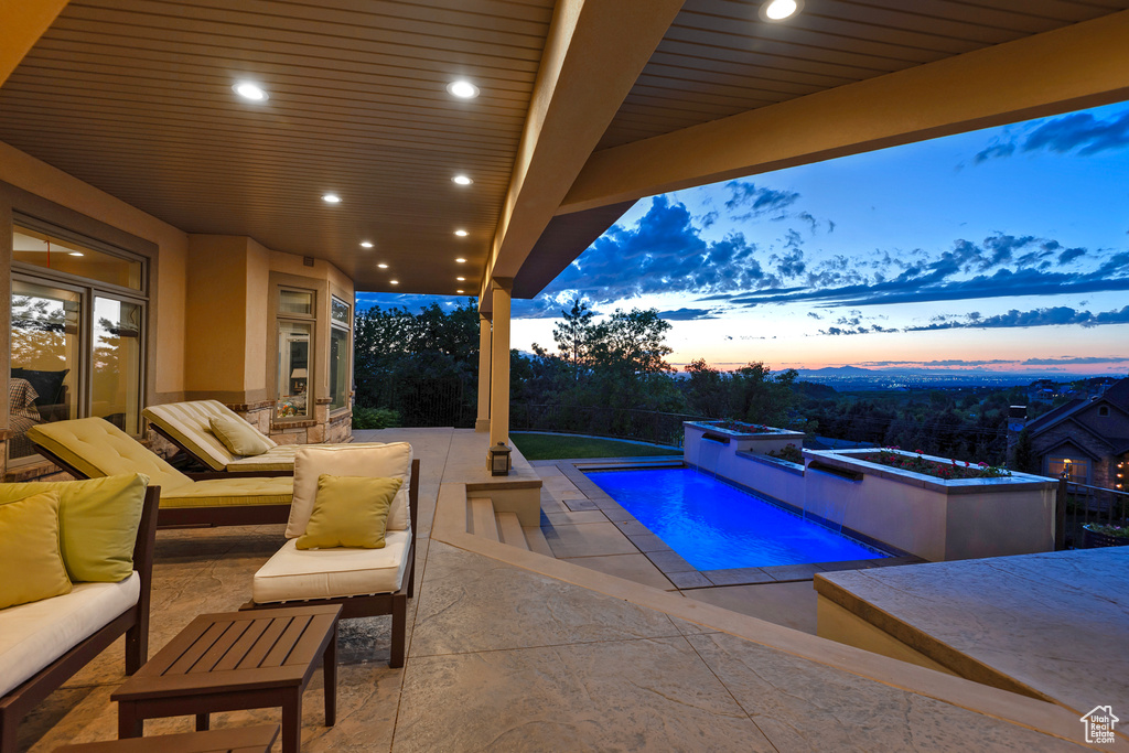 Pool at dusk featuring a patio, an outdoor pool, and an outdoor hangout area