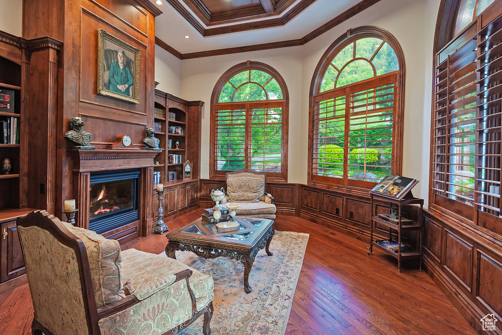 Living area featuring crown molding, a glass covered fireplace, wainscoting, wood finished floors, and recessed lighting