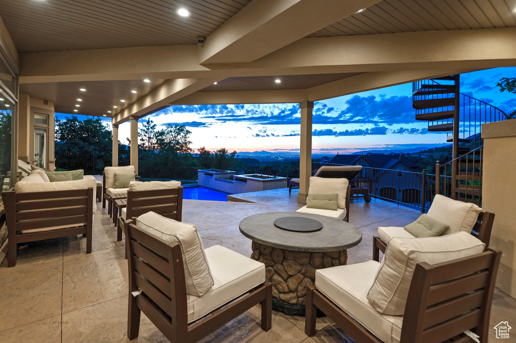 Patio terrace at dusk with stairs, outdoor lounge area, a patio area, a fenced backyard, and a pool with connected hot tub