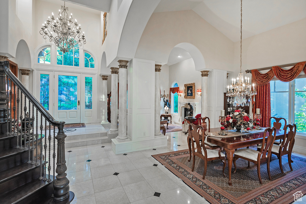 Dining room with high vaulted ceiling, a chandelier, arched walkways, ornate columns, and stairs