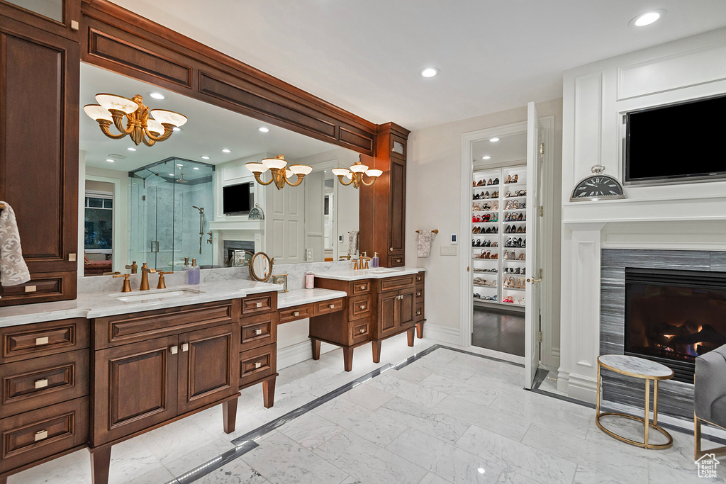 Bathroom featuring a glass covered fireplace, a chandelier, a stall shower, vanity, and baseboards