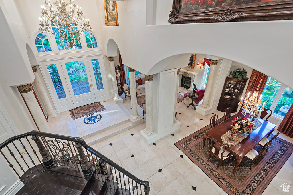 Foyer entrance with arched walkways, a chandelier, a towering ceiling, tile patterned floors, and ornate columns