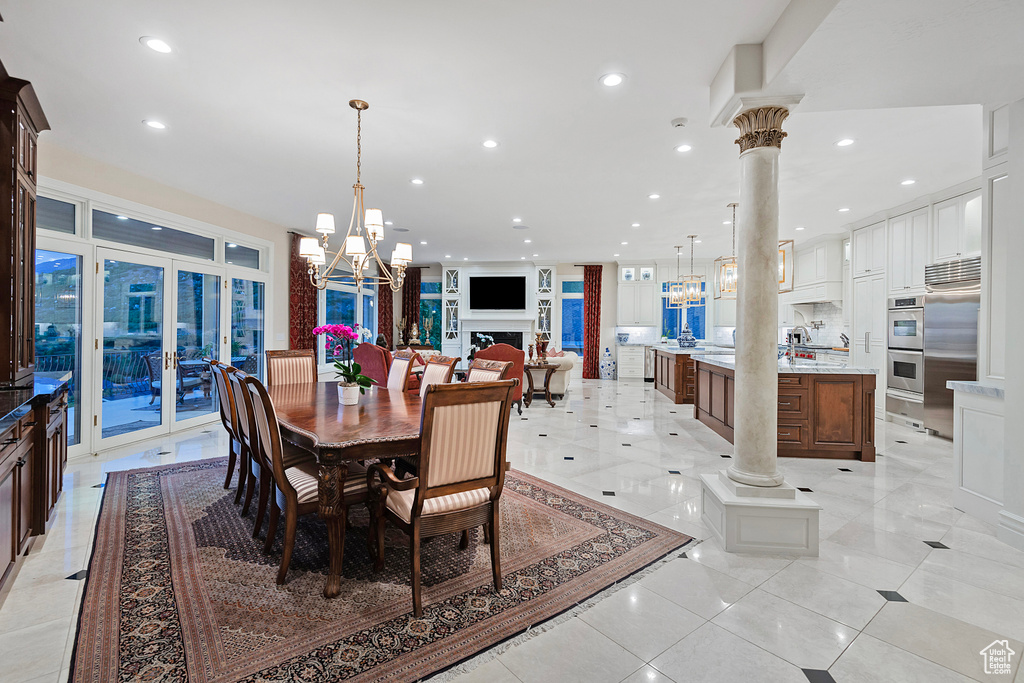 Dining area featuring a chandelier, recessed lighting, french doors, decorative columns, and light tile patterned floors