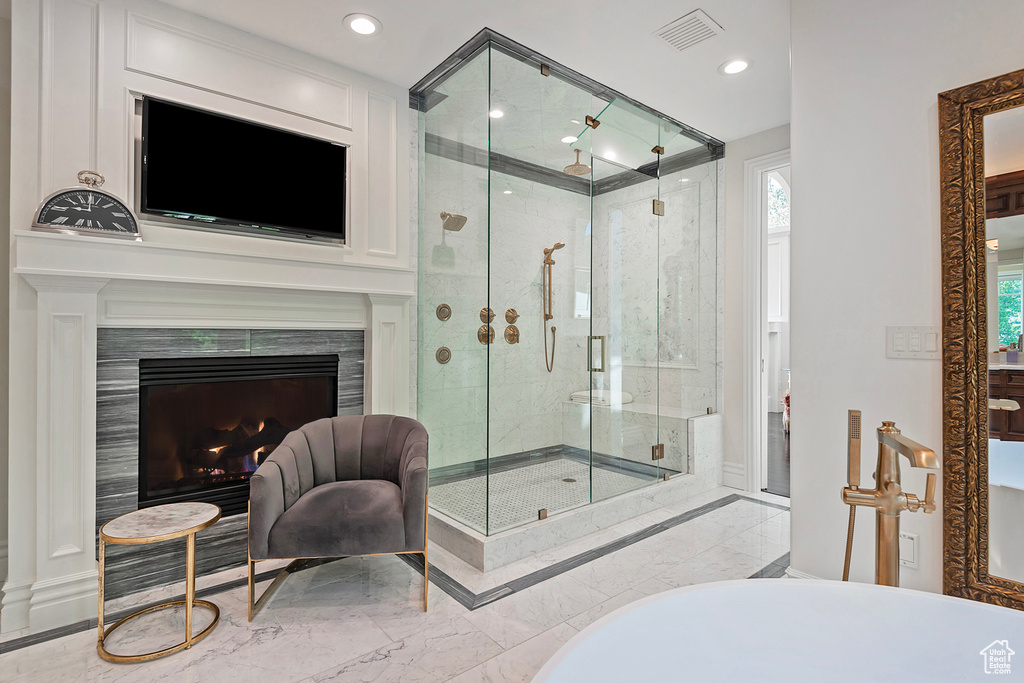 Bathroom featuring a freestanding tub, a stall shower, marble tiled floors, a fireplace, and recessed lighting