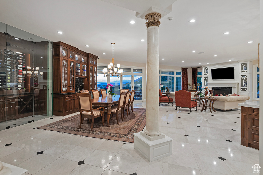 Dining area with a chandelier, decorative columns, light tile patterned floors, recessed lighting, and bar area