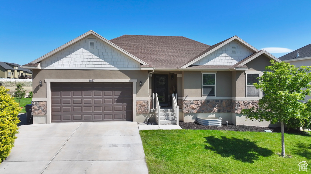 Craftsman-style house with stone siding, stucco siding, an attached garage, a front lawn, and concrete driveway