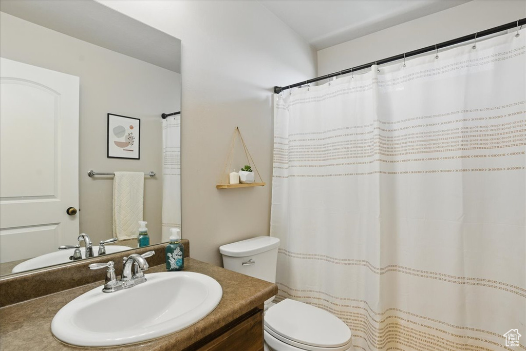 Full bath with toilet, vanity, and curtained shower