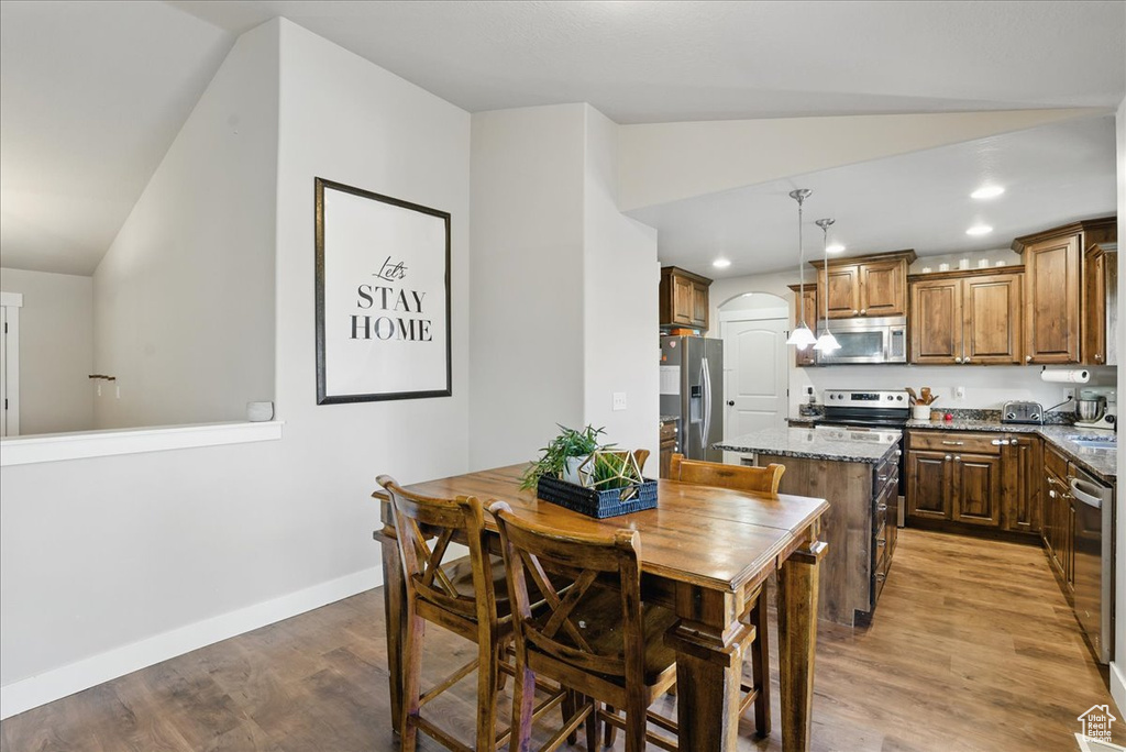 Dining space featuring lofted ceiling, light wood-type flooring, arched walkways, baseboards, and recessed lighting
