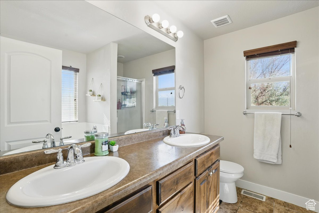 Full bath featuring baseboards, toilet, a shower stall, and double vanity
