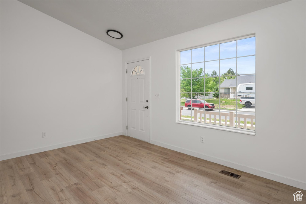 Spare room with wood finished floors, vaulted ceiling, and baseboards