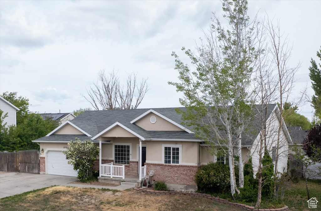 View of front of property featuring brick siding, a porch, concrete driveway, stucco siding, and an attached garage