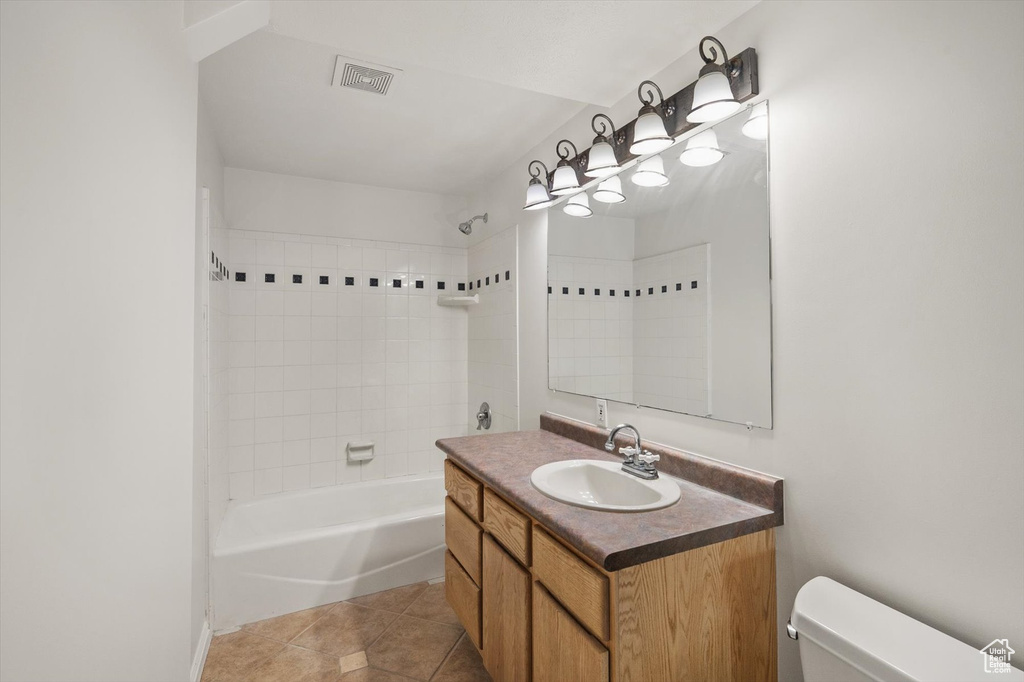 Full bathroom featuring toilet, vanity, shower / bathtub combination, and tile patterned flooring