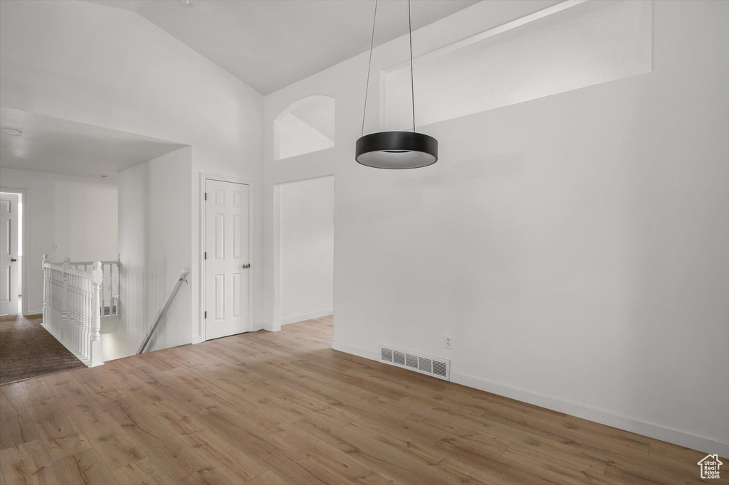 Spare room with high vaulted ceiling, wood finished floors, and baseboards