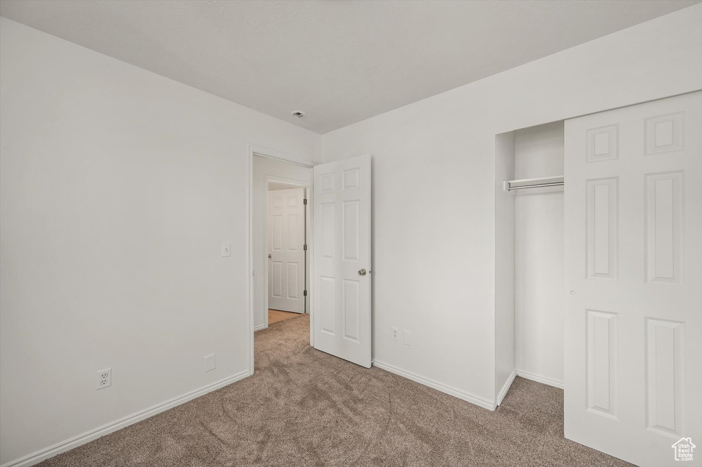 Unfurnished bedroom featuring carpet, baseboards, and a closet
