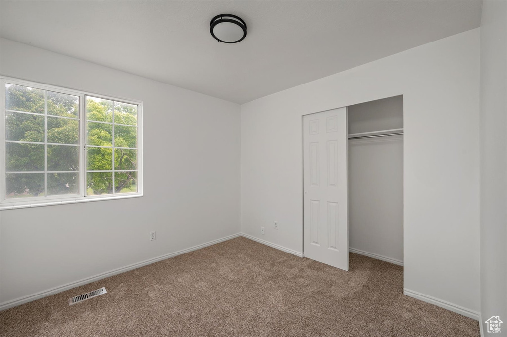 Unfurnished bedroom with carpet floors, baseboards, and a closet
