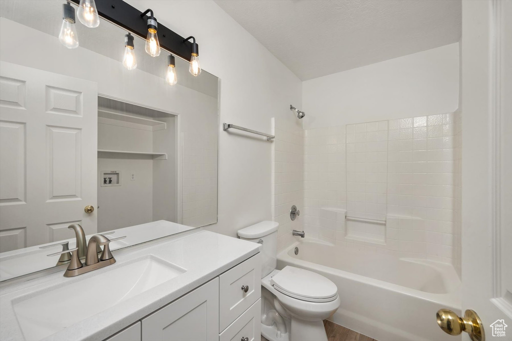 Bathroom featuring vanity, toilet, shower / tub combination, and wood finished floors