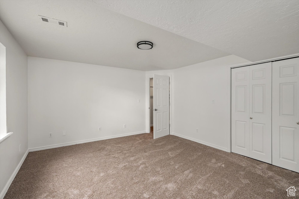 Unfurnished bedroom featuring carpet flooring, baseboards, a closet, and a textured ceiling