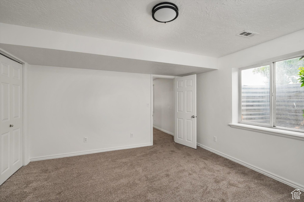 Unfurnished bedroom with carpet floors, a textured ceiling, baseboards, and a closet