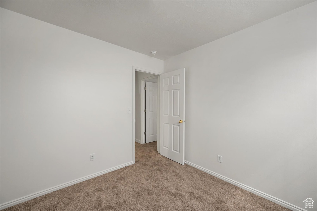 Spare room with light colored carpet, baseboards, and a smoke detector