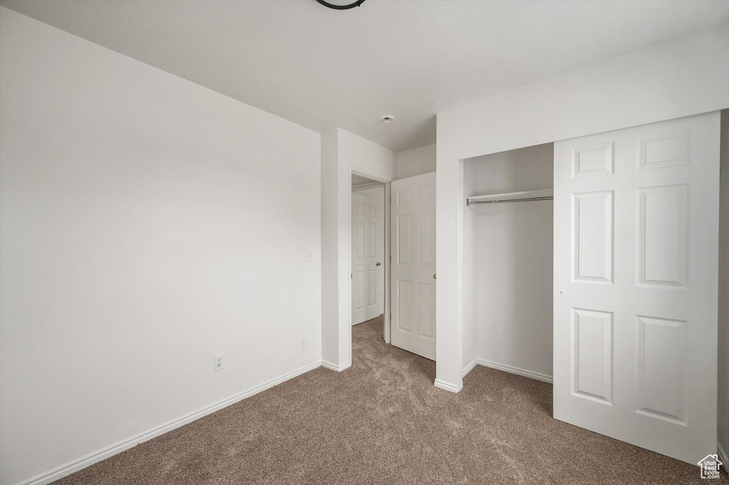Unfurnished bedroom with carpet flooring, baseboards, and a closet