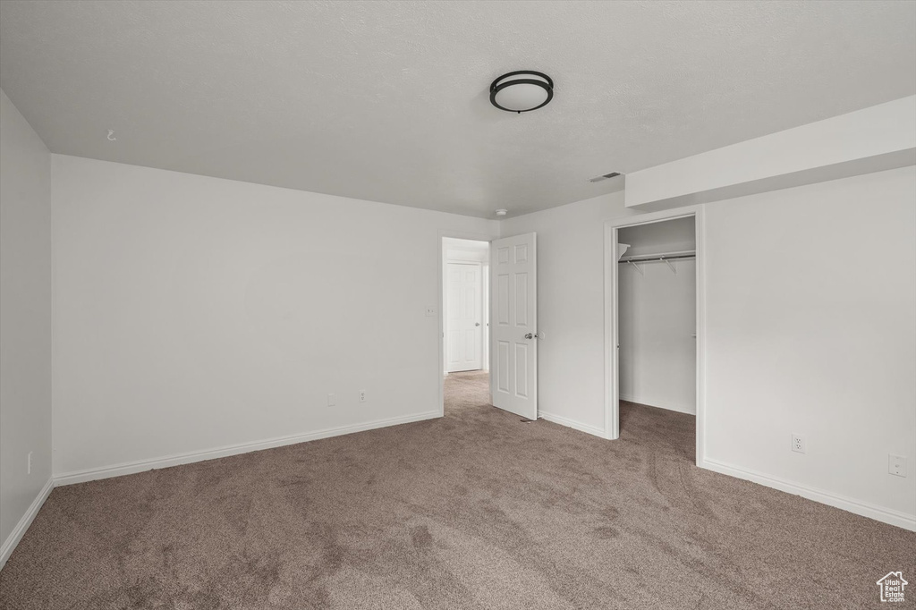 Unfurnished bedroom with carpet flooring, baseboards, a closet, and a walk in closet